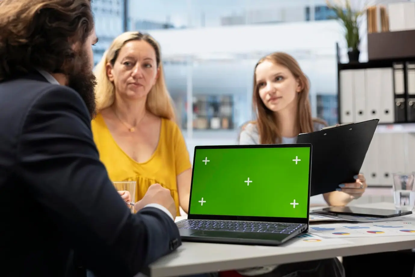 Клиенты проверяют инвестиционный план на ноутбуке с хромакеем.